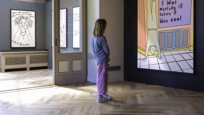 Galerieblick mit Besucher, der ein gelb-lila Textwerk von Robbie Williams im Moco Museum Amsterdam betrachtet.