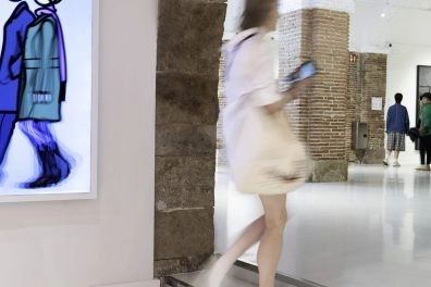 Visitor viewing blue cartoon-style artwork by Opie through stone arch at Moco Museum Barcelona. Visitor viewing blue cartoon-style artwork by Opie through stone arch at Moco Museum Barcelona.