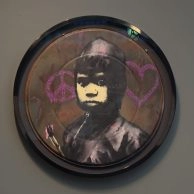 Banksy's Peace & Love Glitter, San Francisco, 2010, portret van ME-agent met roze harten, te zien in Amsterdam. Banksy's Peace & Love Glitter, San Francisco, 2010, portret van ME-agent met roze harten, te zien in Amsterdam.