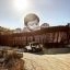 Large-scale installation by JR of a toddler peering over the US-Mexico border wall, with a border patrol vehicle below.