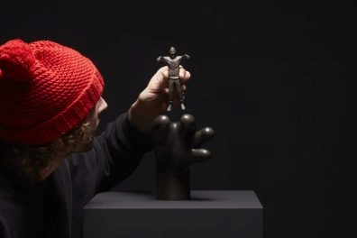 Frankey placing a small bronze figure on a surreal black sculpture, part of Planet Positive Disruption, Moco Museum Amsterdam.