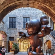 Groups entering courtyard with large KAWS sculpture at Moco Museum Barcelona.