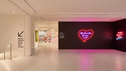 Interior of Moco Museum London with neon heart artwork by Tracey Emin on black wall and colorful graffiti in background