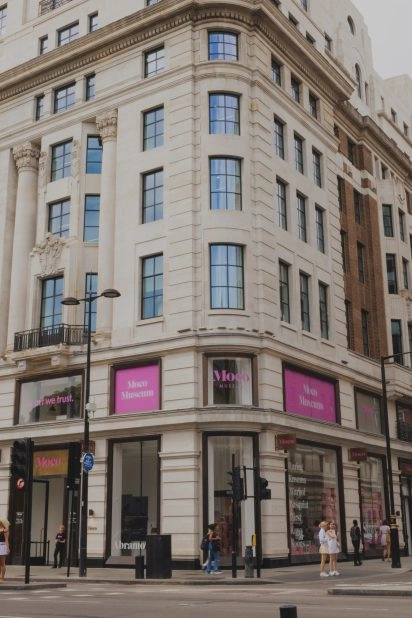 Vue extérieure du Moco Museum London dans un bâtiment historique avec enseignes roses et expositions de Banksy, Basquiat, Warhol, Arsham, Hirst et Koons