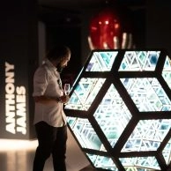 Visitors viewing mirrored hexagonal installation by Anthony James with digital text at Moco Museum London