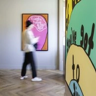Bezoeker loopt langs kleurrijk tekstkunstwerk in Moco Museum Amsterdam. Bezoeker loopt langs kleurrijk tekstkunstwerk in Moco Museum Amsterdam.