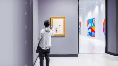 Personne photographiant une œuvre de Banksy au Moco Museum Barcelone